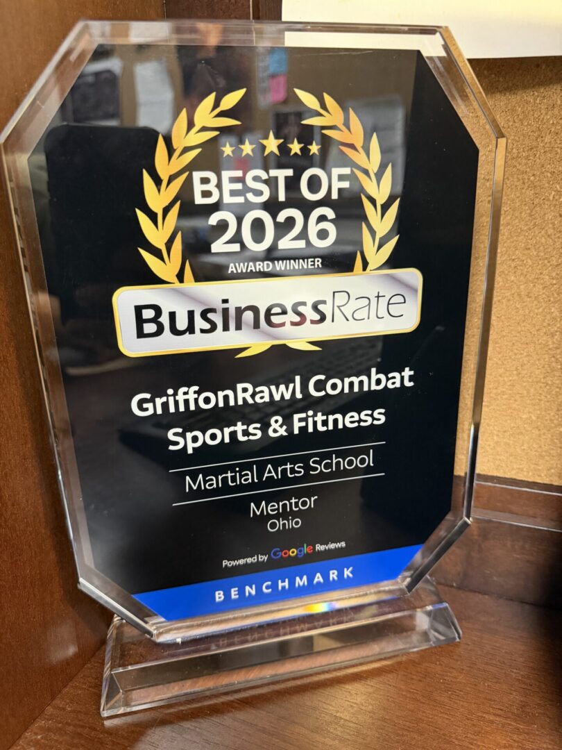 Glass award on a wooden surface with the text "Griffon Rawl Combat Sports & Fitness of 2026" written on it
