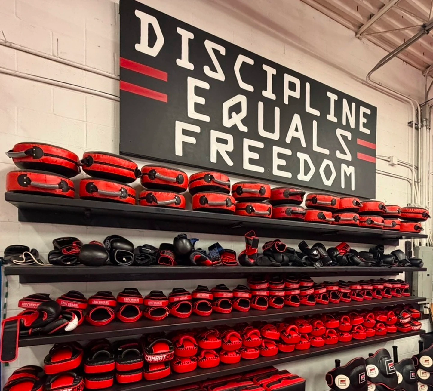 Wall with a board that reads "" and a rack of red and black boxing gloves